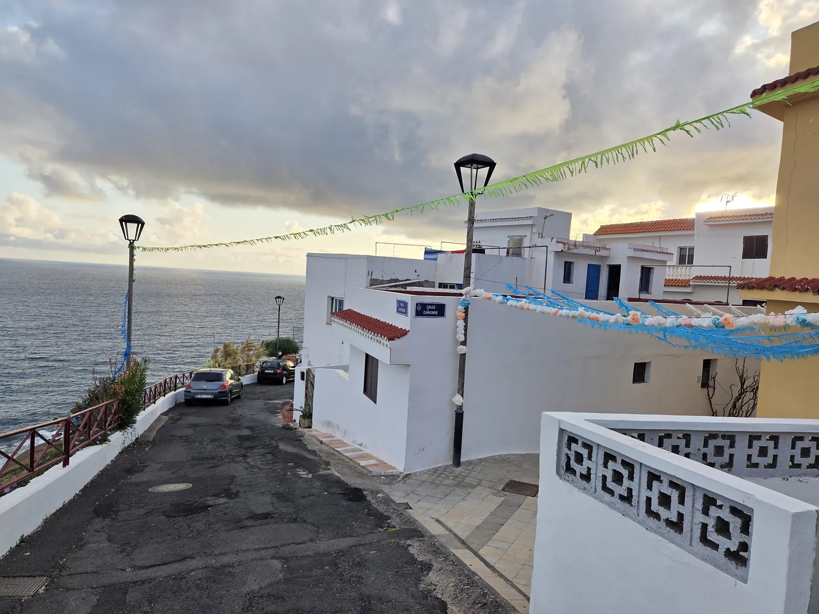 Calle en pendiente entre casas blancas de Almáciga con el océano al fondo
