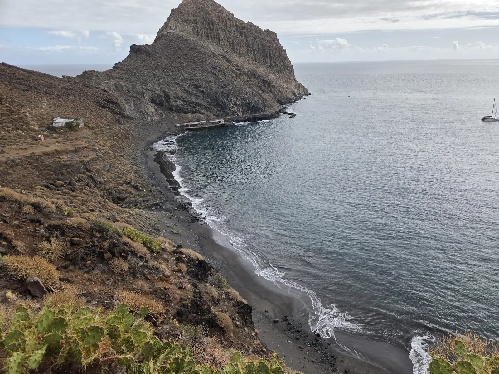 Playa aislada de arena oscura junto a un gran promontorio rocoso en Antequera