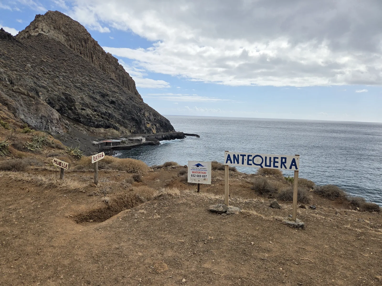 Cartel con el nombre de Antequera frente a la cala y el océano