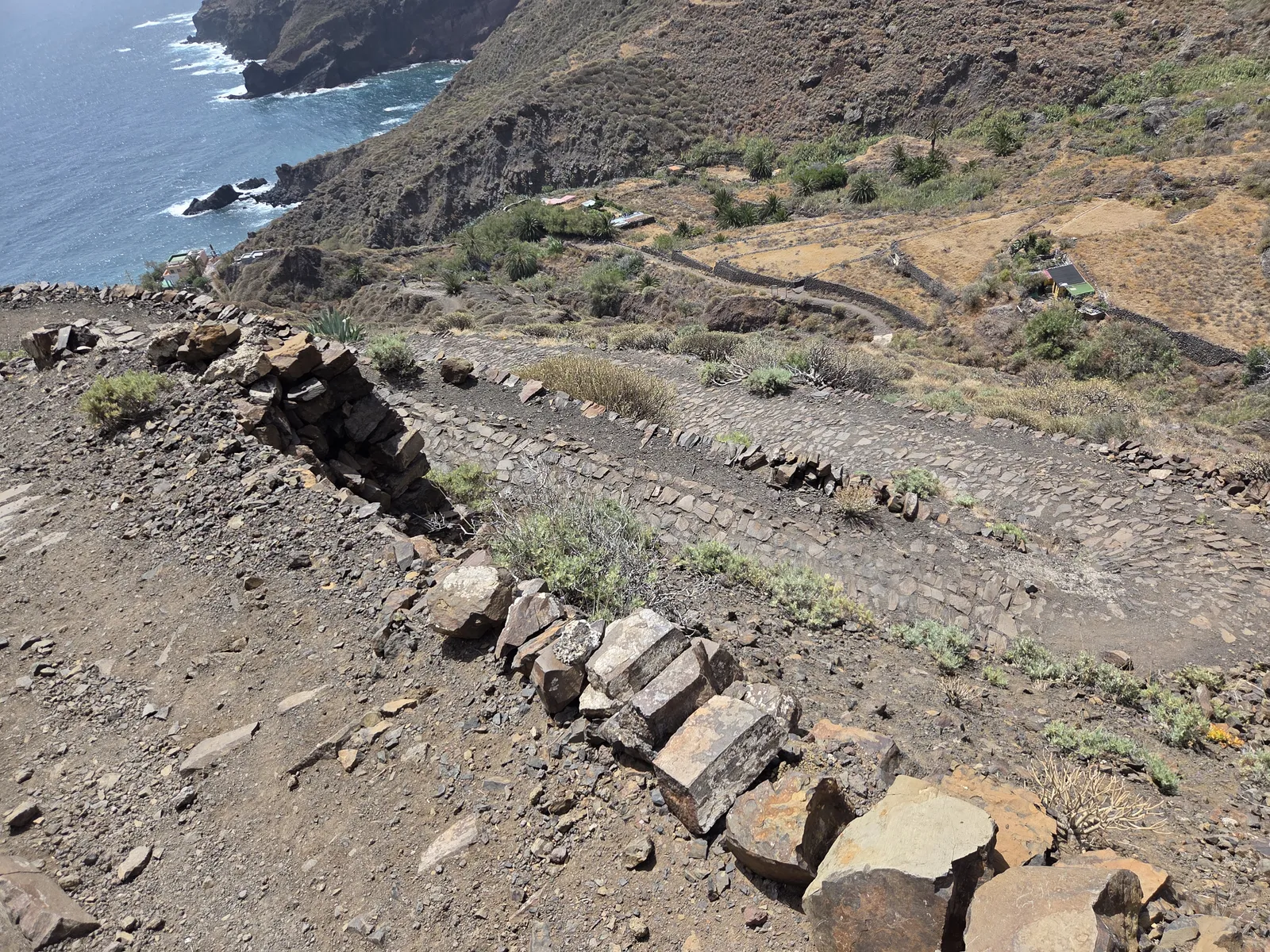 Camino de piedra en descenso por una ladera sobre la costa de Anaga