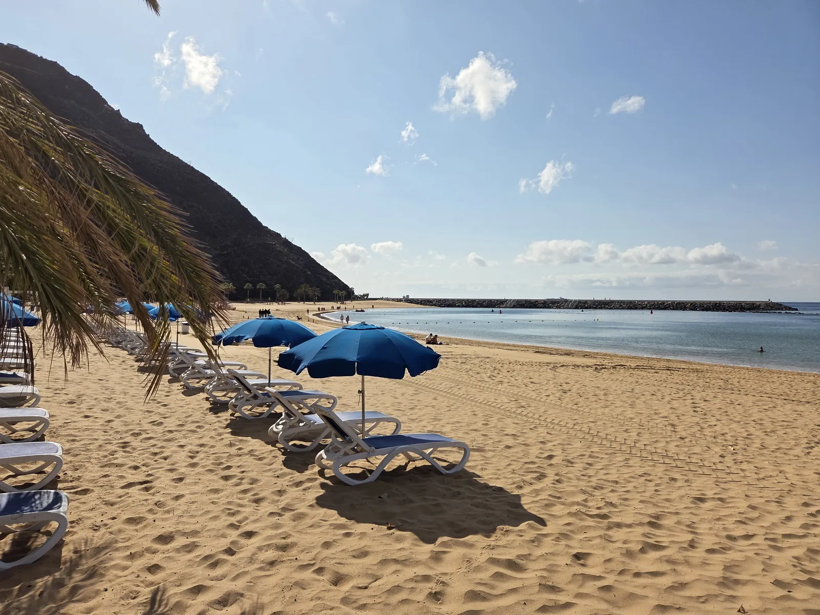Arena de Las Teresitas con hamacas, sombrillas y el rompeolas al fondo