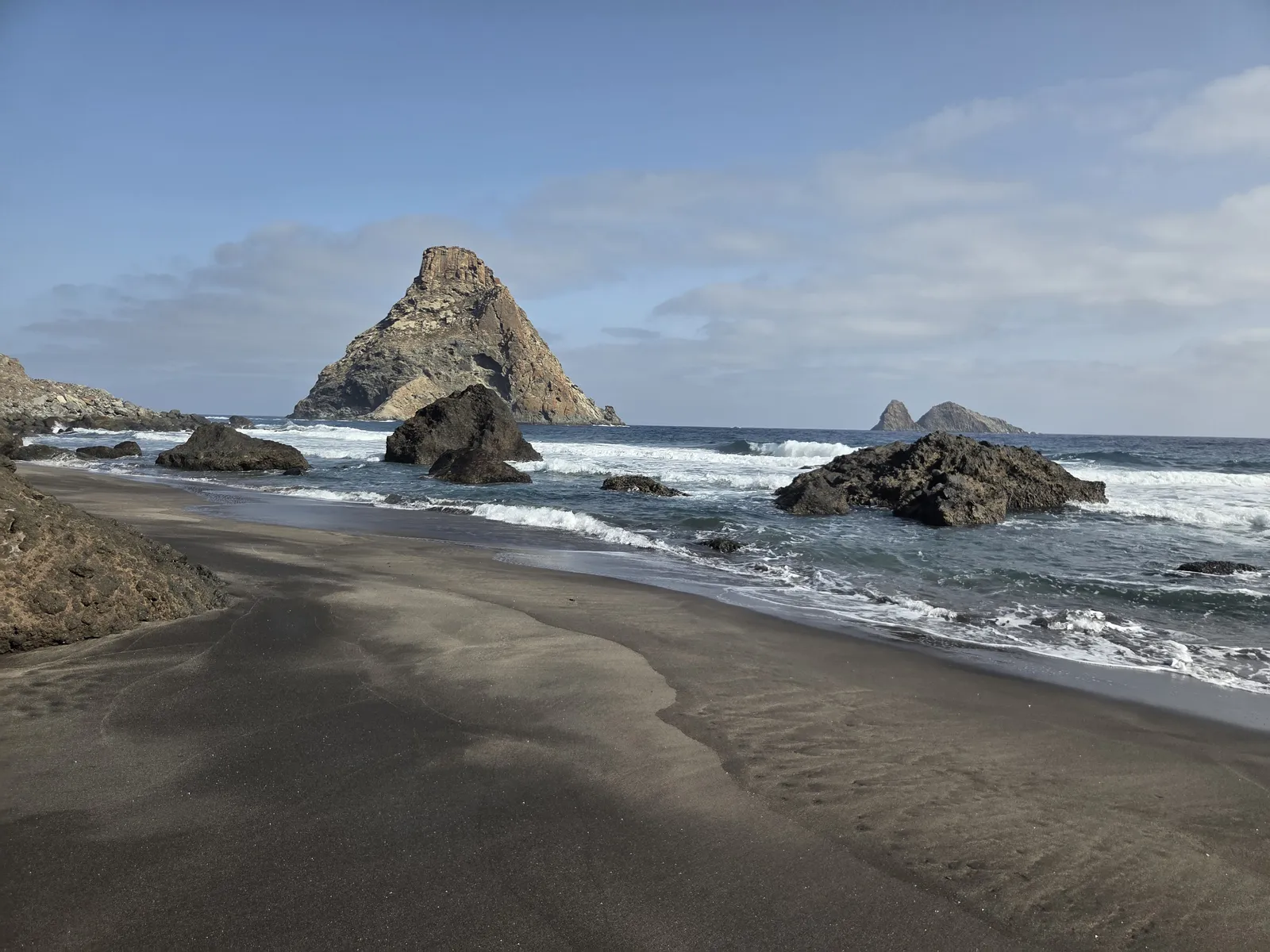 Playa de arena negra con grandes roques volcánicos frente a la costa de Anaga