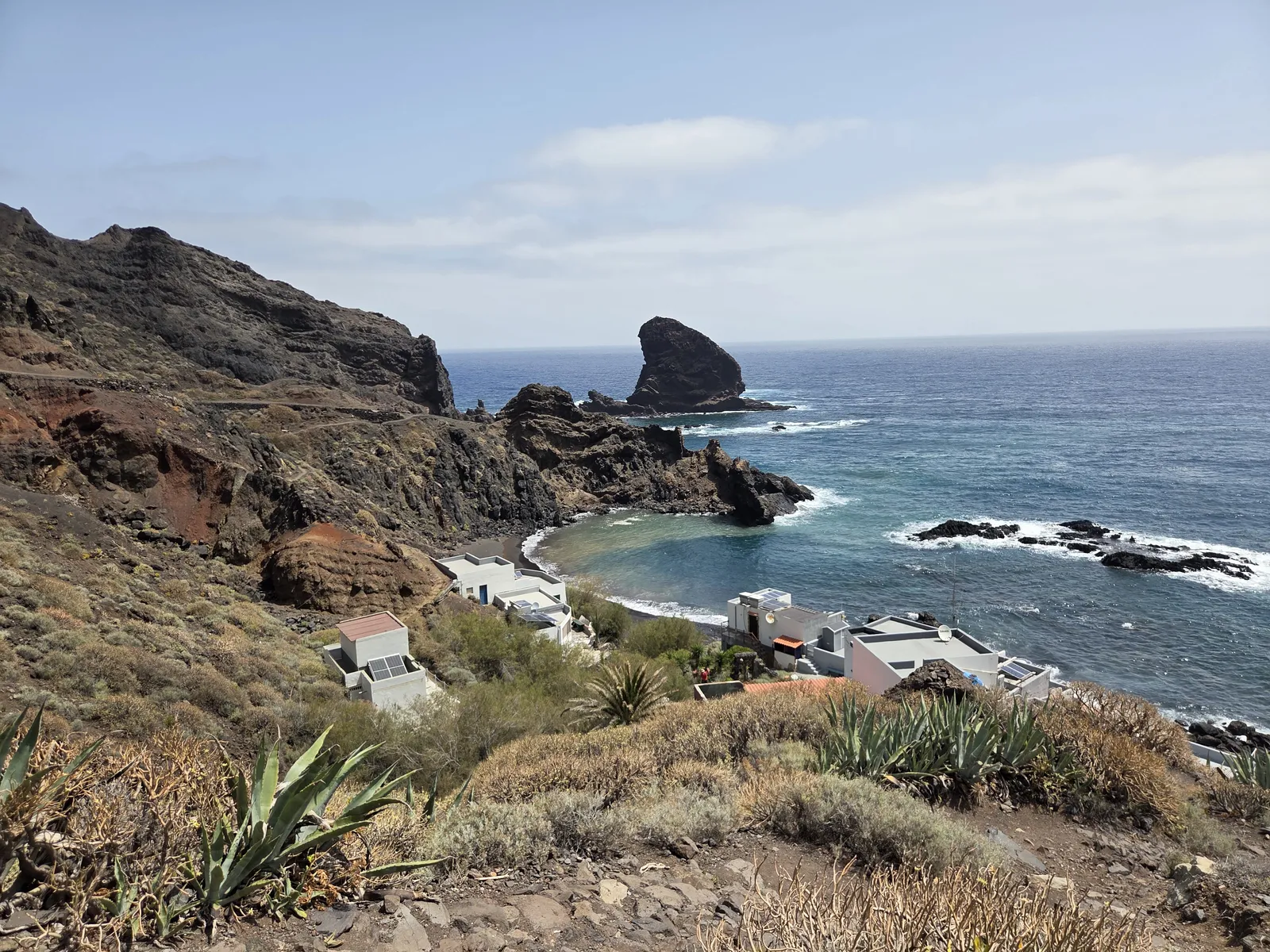 Casas de Roque Bermejo junto a una cala volcánica y un roque marino